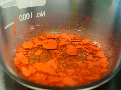 Ferrocene powder, an organometallic chemical synthesized in a laboratory. Detail of its bright orange color, typical of this molecule.