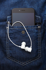smartphone mobile in Blue jeans shirt pocket with black screen and white earphones