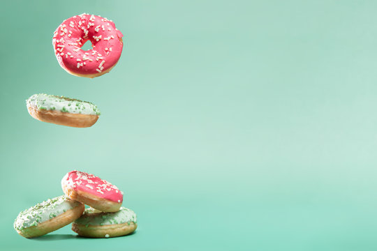 Donuts with pink and green icing with sprinkles on mint backround with copyspace for your text
