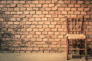An empty chair against a brickwall