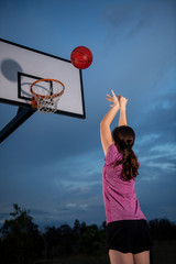 Girl shooting a basketball at an outdoor court