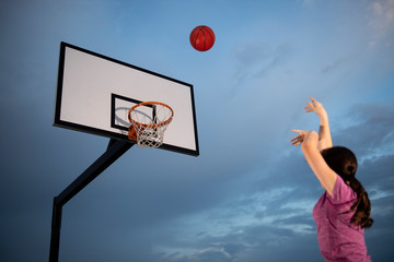 Girl shooting a basketball at an outdoor court