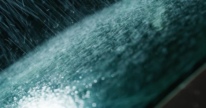 Super close up of a carglass while it&rsquo;s raining, the wipers are taking off the water from it. Concept: thunderstorm, car, weather. Shot on Red Camera 8K