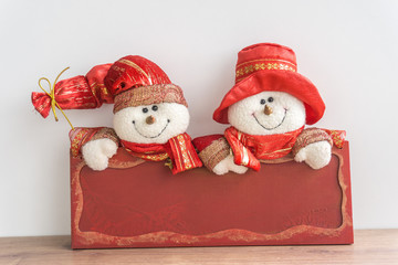 Snowmen with red board written merry christmas in english on white background