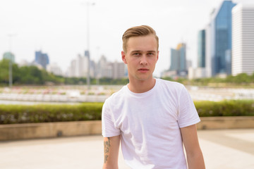 Young handsome man with blond hair relaxing at the park