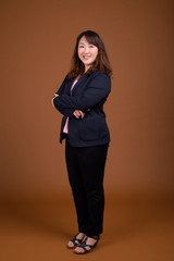 Mature beautiful Asian businesswoman against brown background