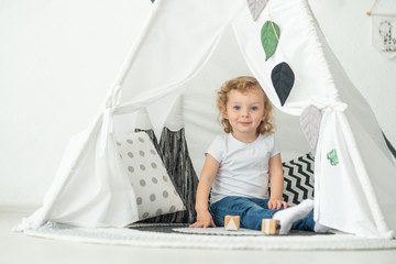 Big bright wigwam baby plays in a bright room © Anton
