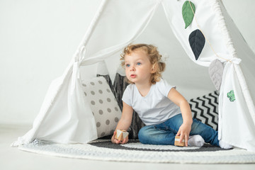 Big bright wigwam baby plays in a bright room © Anton