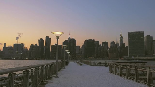 View down snow-covered Long Island City Pier at Dusk with Manhattan Skyline across East River, Gantry Plaza State Park, LIC