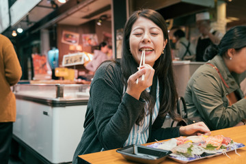 beautiful tourist trying sashimi.