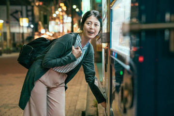 lady buying drink from vending machine at night