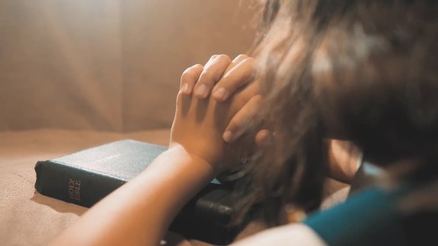 Little girl praying in the night. Little girl hand praying. little girl lifestyle holy bible prays with bible in her hands. the catholicism sacred holy bible. children and religion upbringing faith