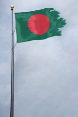 Worn and tattered Bangladesh flag blowing in the wind on a cloudy day
