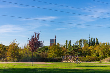 Scenery of Nordstern park, former coal mine area, man cycling, small hill and background of Nordsternturm and  Zeche Nordstern.