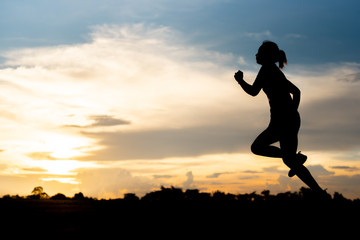 Fototapeta na wymiar silhouette woman running alone at beautiful sunset in the park.