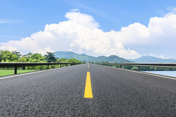 Asphalt road and green mountain under the blue sky