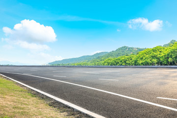 Asphalt road and green mountain under the blue sky