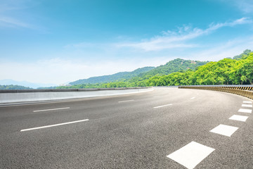Asphalt road and green mountain under the blue sky
