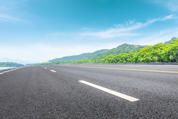 Asphalt road and green mountain under the blue sky