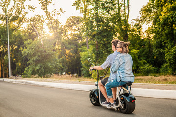 Lovely young couple driving electric bike during summer Modern city life and transportation