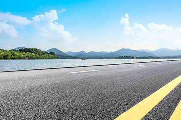 Asphalt road and beautiful mountain with lake under the blue sky