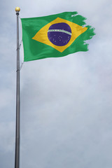 Worn and tattered Brazil flag blowing in the wind on a cloudy day