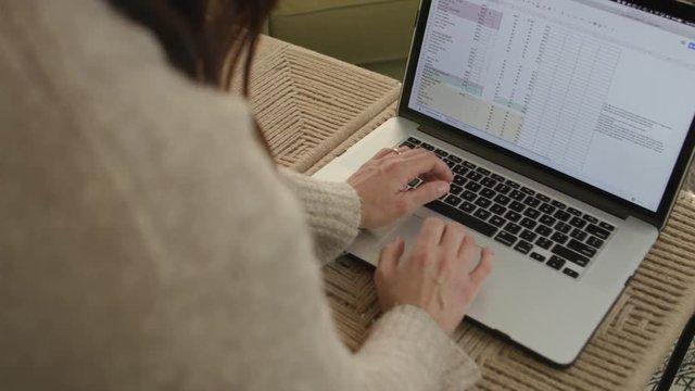 4k over the shoulder shot of brunette female entering data into budget spreadsheet