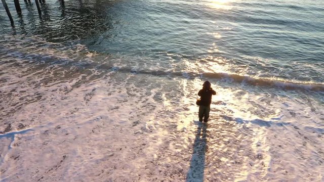 Man fishing at sunrise at Belmar beach, New Jersey.