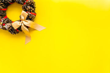 Christmas wreath made of pine cones on yellow background top view space for text