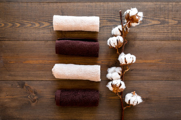 Cotton towels high quality. Set of towels twisted coil near dry cotton flowers on dark wooden background top view copy space