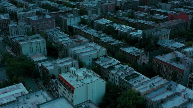Downward drone shot of buildings in the Harlem neighborhood of New York City.  Clear smooth sunset shot of rooftops and churches and local traffic.  in 4k.