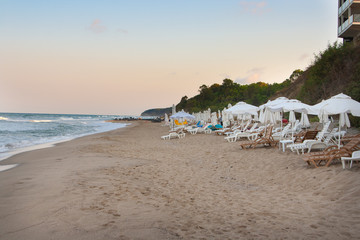 Fototapeta premium Empty beach on the seaside at the end of resort season with many empty sun loungers and umbrellas in the evening