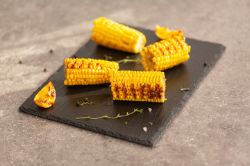 Grilled corn grilled on fire. On a dark stone table.