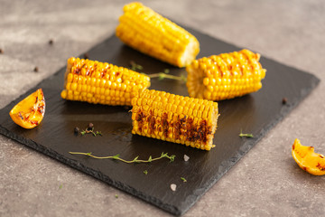 Grilled corn grilled on fire. On a dark stone table.