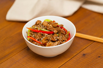 Noodles with pork, vegetables and sesame. On a wooden table.