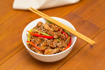 Noodles with pork, vegetables and sesame. On a wooden table.