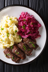 German beef rouladen recipe, along with mashed potato and red cabbage close-up. Vertical top view