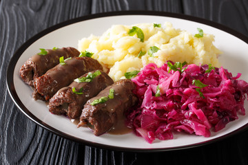 Beef rolls with mustard, bacon and pickles served with mashed potatoes and red cabbage close-up. horizontal