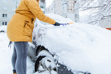 Fototapeta na wymiar woman cleaning her car of snow after snowstorm