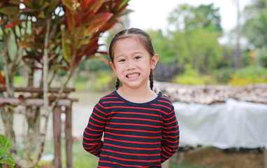 Portrait of smiling little Asian child girl looking at you in the garden outdoor.