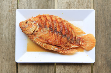 Deep fried Ruby fish on white square plate against wooden table - Famous Thai food menu.