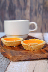 Egg tart and a cup of coffee on wooden background