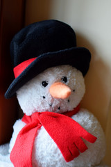 New year snowman plush toy with black hat and red scarf as merry christmas or xmas decoration closeup view. Happy winter holiday and party celebration concept.