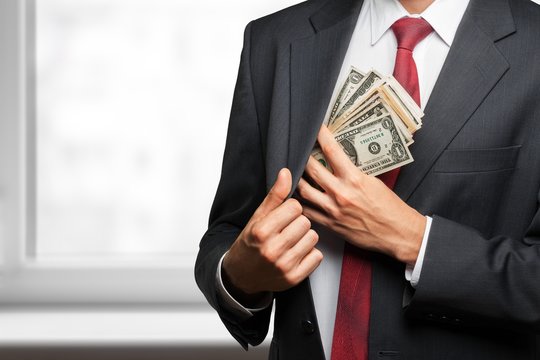 Pocketing company money.  businessman placing money into his
