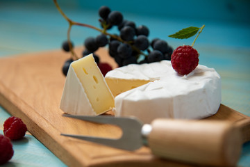 cheese camembert with raspberries and grapes on table