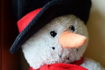 New year snowman plush toy with black hat and red scarf as merry christmas or xmas decoration closeup view. Happy winter holiday and party celebration concept.