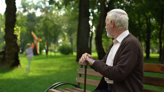 Lonely grandfather remembering his happy childhood, sitting in park alone