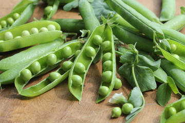Ripe pods of green peas, fresh green peas on wooden table, close up
