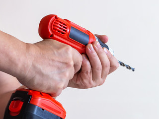 Man holds in the hands of orange electric drill on batteries
