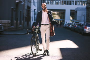 Businessman going to office with bicycle using phone